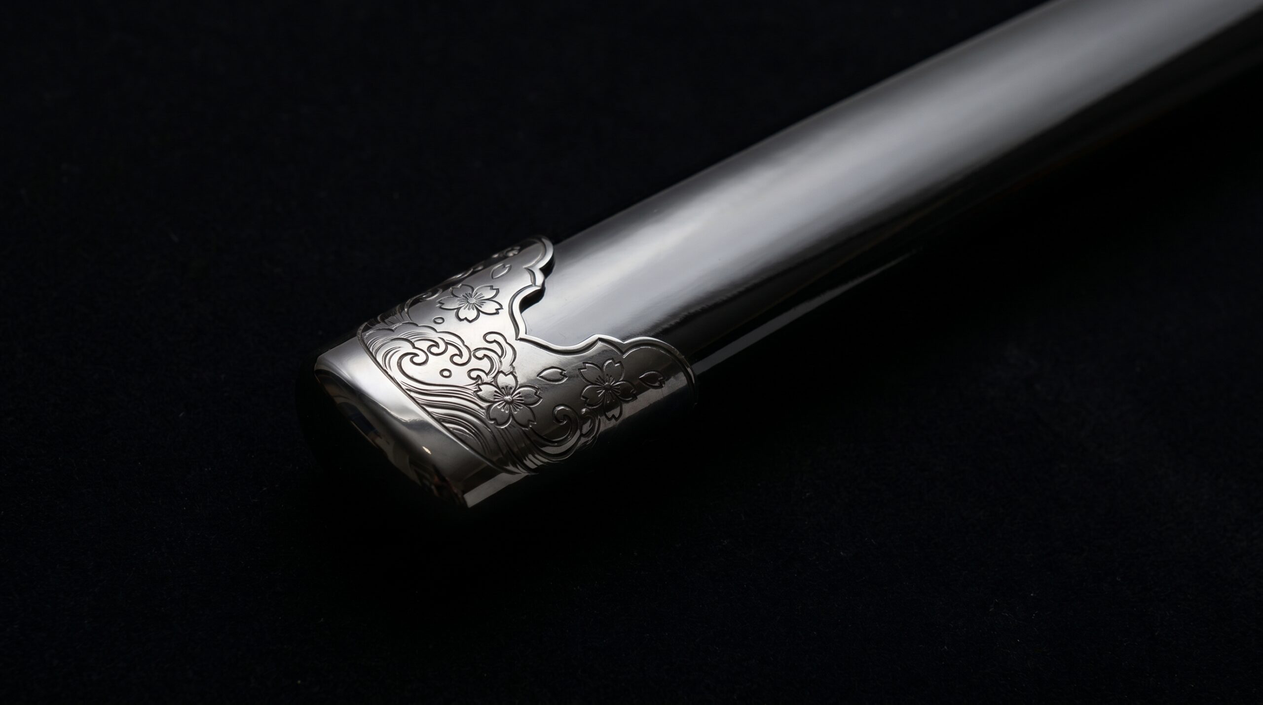 Close-up of a kojiri end cap on a black-lacquered katana saya